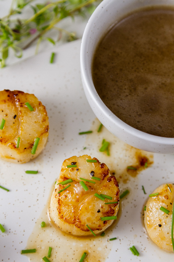 Vanilla Dusted Scallops seared sea scallops with pan sauce on a white plate