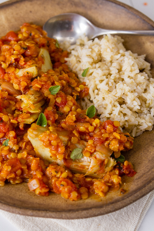 Red Lentil and Artichoke Stew with perfectly cooked brown rice in a brown bowl with a spoon