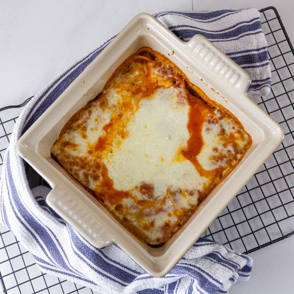 top down looking at the Spinach Provolone Baked Pasta casserole dish right when it came out of the oven. It's on a blue towel and on a wire cooling rack 