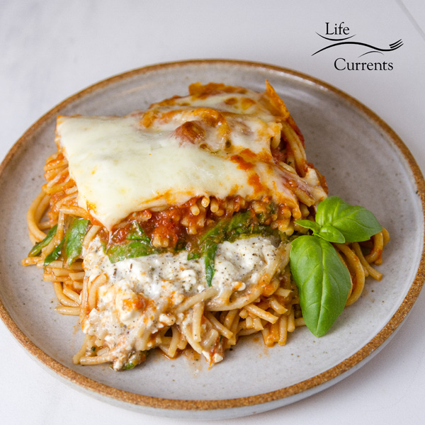 Spinach Provolone Baked Pasta on a plate with a garnish of fresh basil