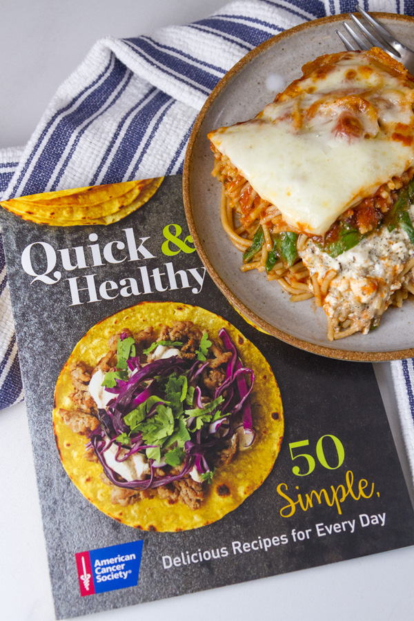 Spinach Provolone Baked Pasta from the book Quick & Healthy 50 Simple, Delicious Recipes for Every Day by the American Cancer Society both the book and the meal are pictures with a blue striped towel