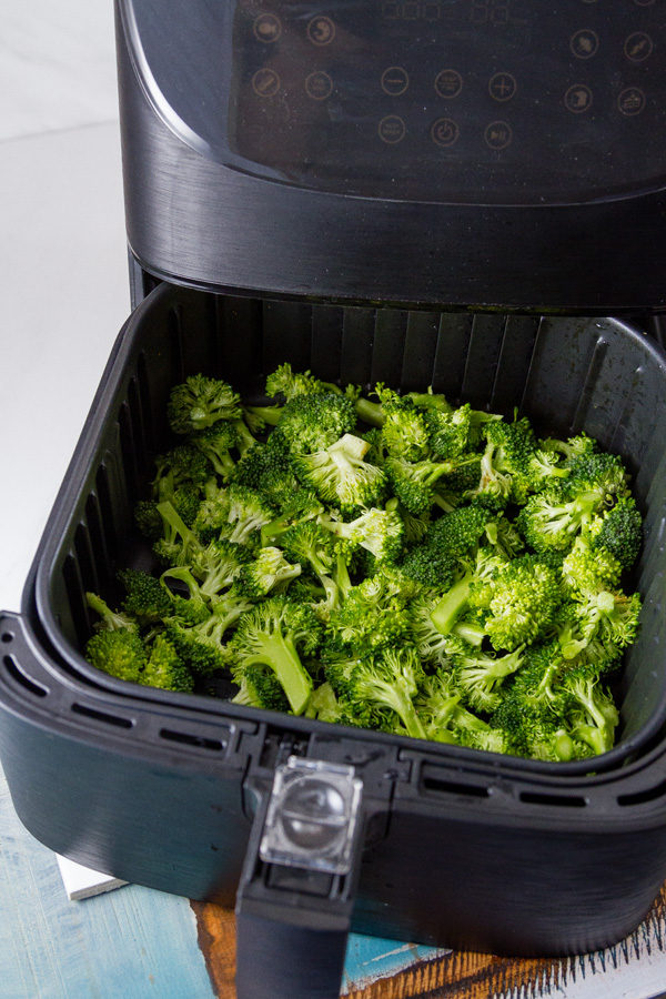 broccoli in the basket of the air fryer ready to cook for Air Fryer Roasted Broccoli
