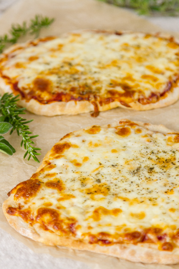 No yeast flatbreads made into pizzas - two of them - with some herbs around 