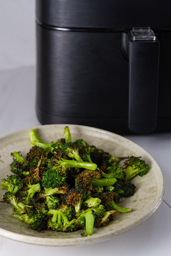 Air Fryer Roasted Broccoli in a bowl in front of the air fryer