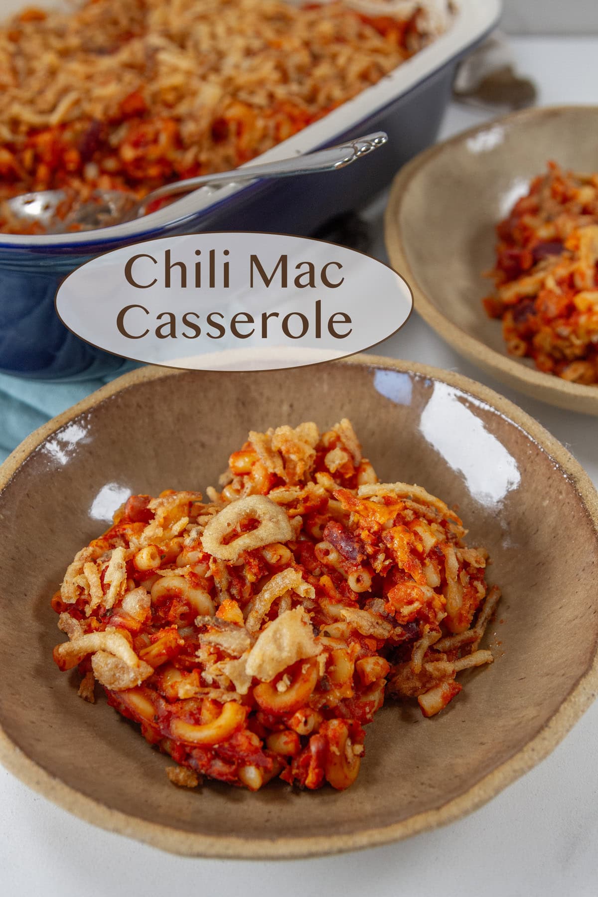 a bowl of chili mac casserole served in front of the baking dish of the casserole.