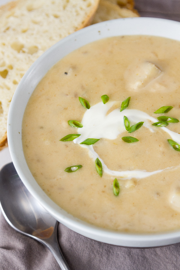 Rich and creamy, perfect comfort food. This Pepper Jack Potato Soup (or is it a chowder?) is so good and so easy to make. This is one your family will ask for again and again. close up of a bowl of Pepper Jack Potato Soup with slices of bread and a spoon