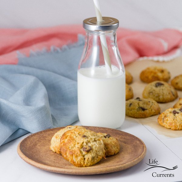 Coconut Almond Meal Cookies with Chocolate Chips on a plate with a glass of milk and the cookies in the background, square crop