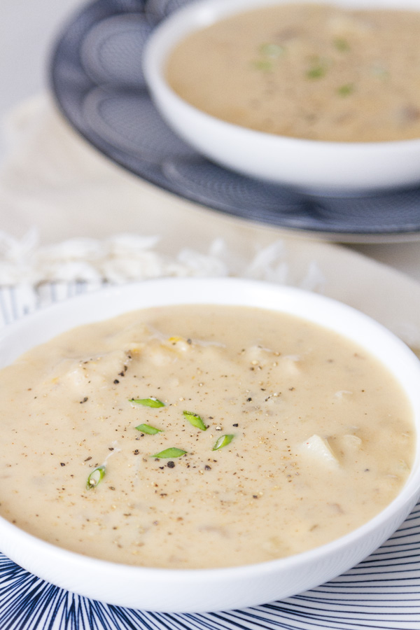 Rich and creamy, perfect comfort food. This Pepper Jack Potato Soup (or is it a chowder?) is so good and so easy to make. This is one your family will ask for again and again. Two bowls of Pepper Jack Potato Soup on blue patterned plates garnished with chives