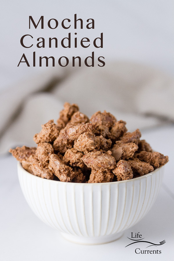 Mocha Candied Almonds in a white bowl on a white background with a grey napkin in the back