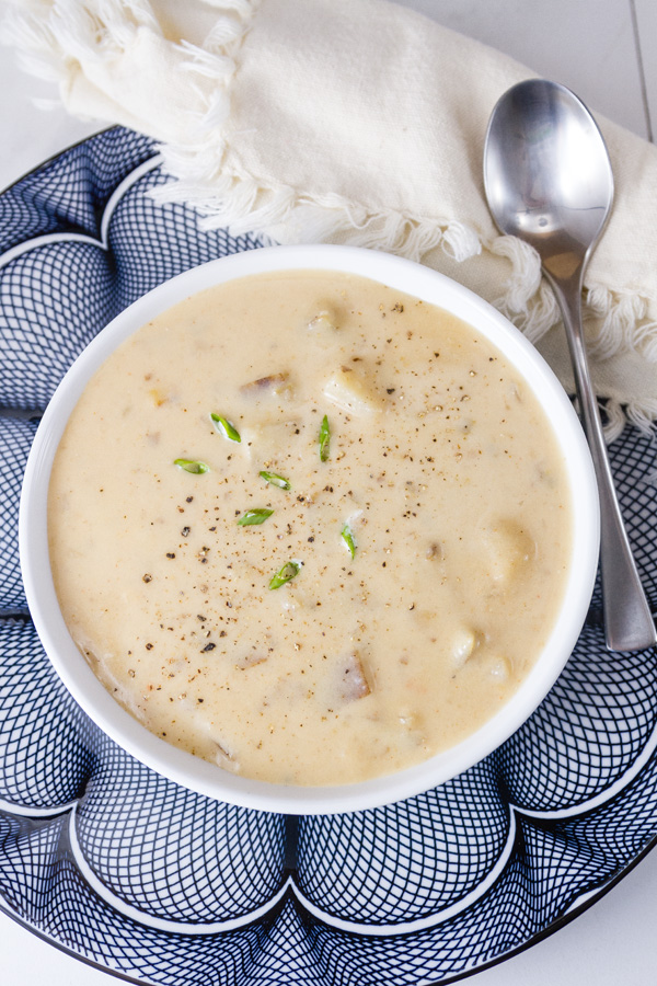 Rich and creamy, perfect comfort food. This Pepper Jack Potato Soup (or is it a chowder?) is so good and so easy to make. This is one your family will ask for again and again. Pepper Jack Potato soup in a white bowl on a blue patterned plate with a spoon and a cloth napkin