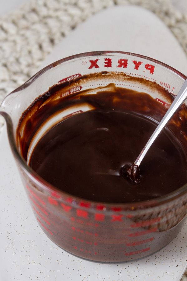 Chocolate Pudding in the glass Pyrex measuring cup that it was cooked in with a spoon on a white background
