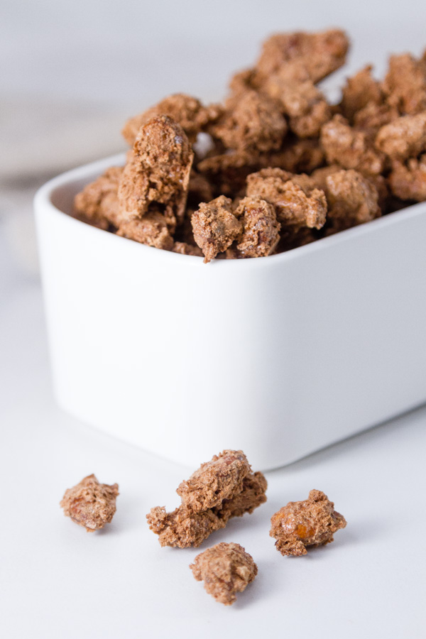 Mocha Candied Almonds in a white serving dish with some spilled out in front