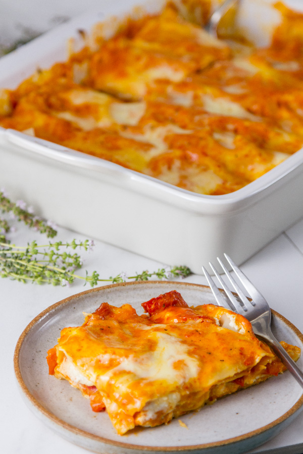 Red Pepper Lasagna - one serving on a plate with the casserole in the background