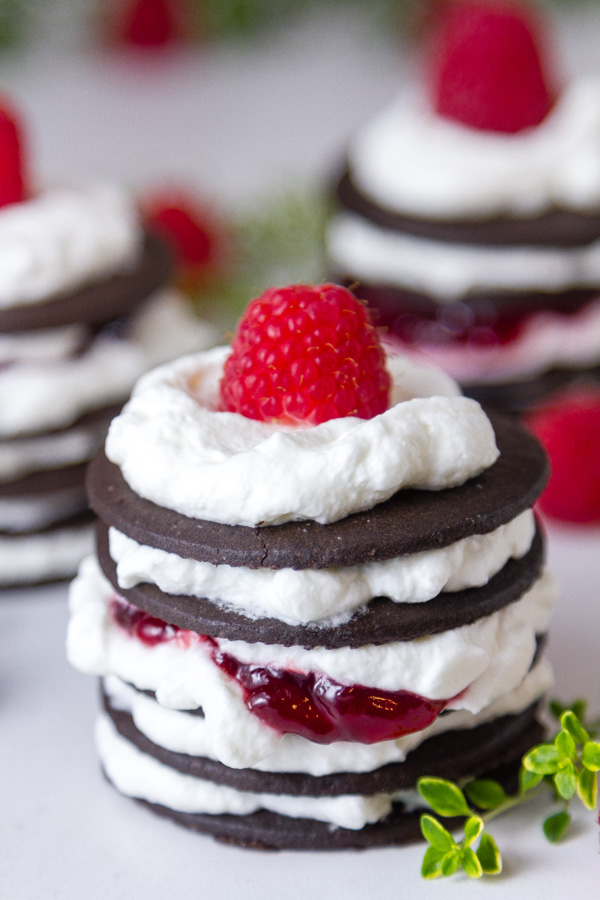 close up of Chocolate Raspberry Icebox Cakes with two more in the background and a thyme sprig for color