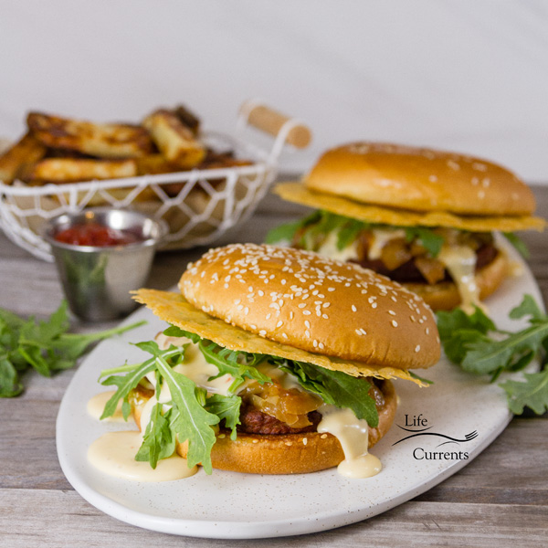 Two Monster Cheese Burgers on a white platter served with fries and ketchup