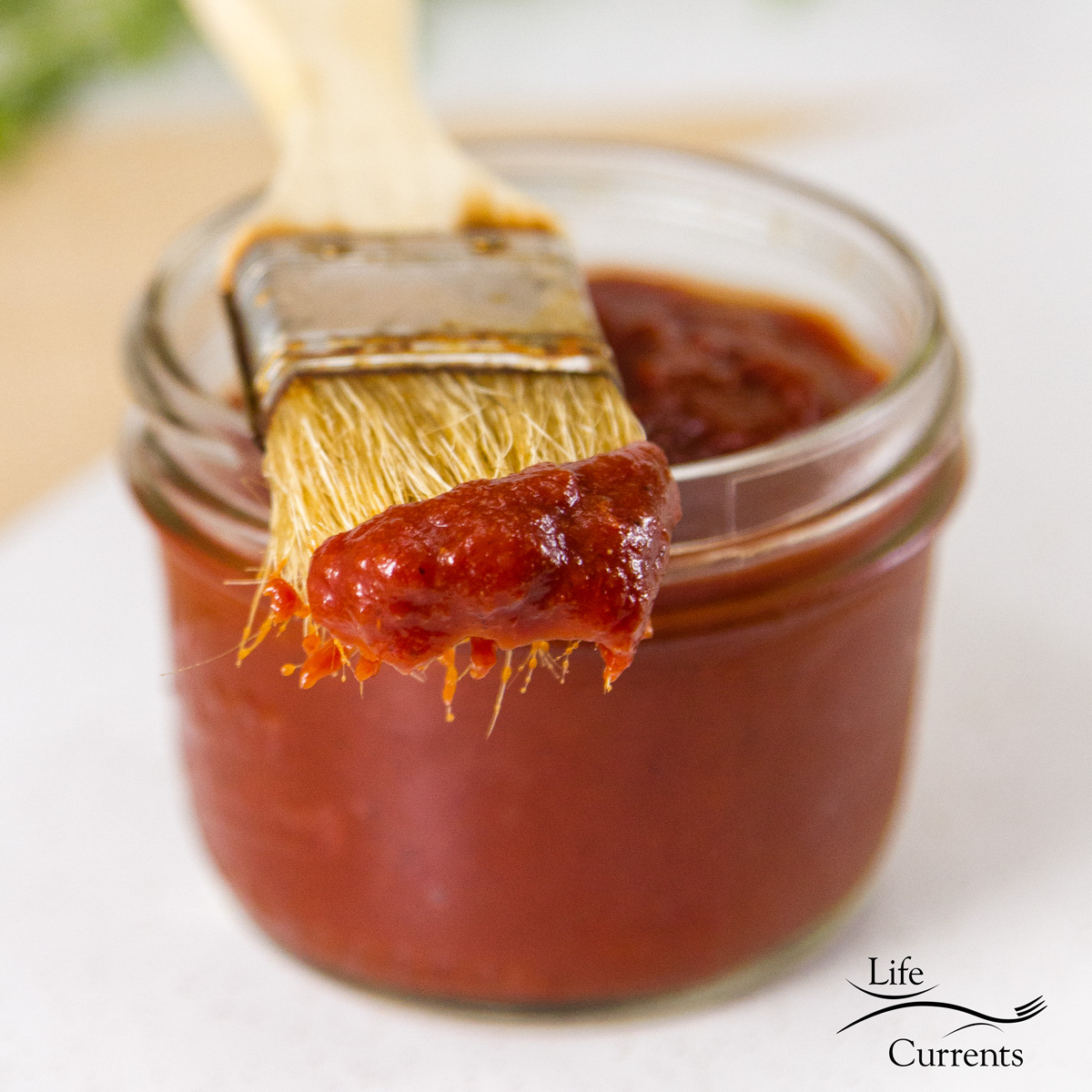 Zesty No-Cook BBQ Sauce in a jar with a brush that's been dipped in the sauce