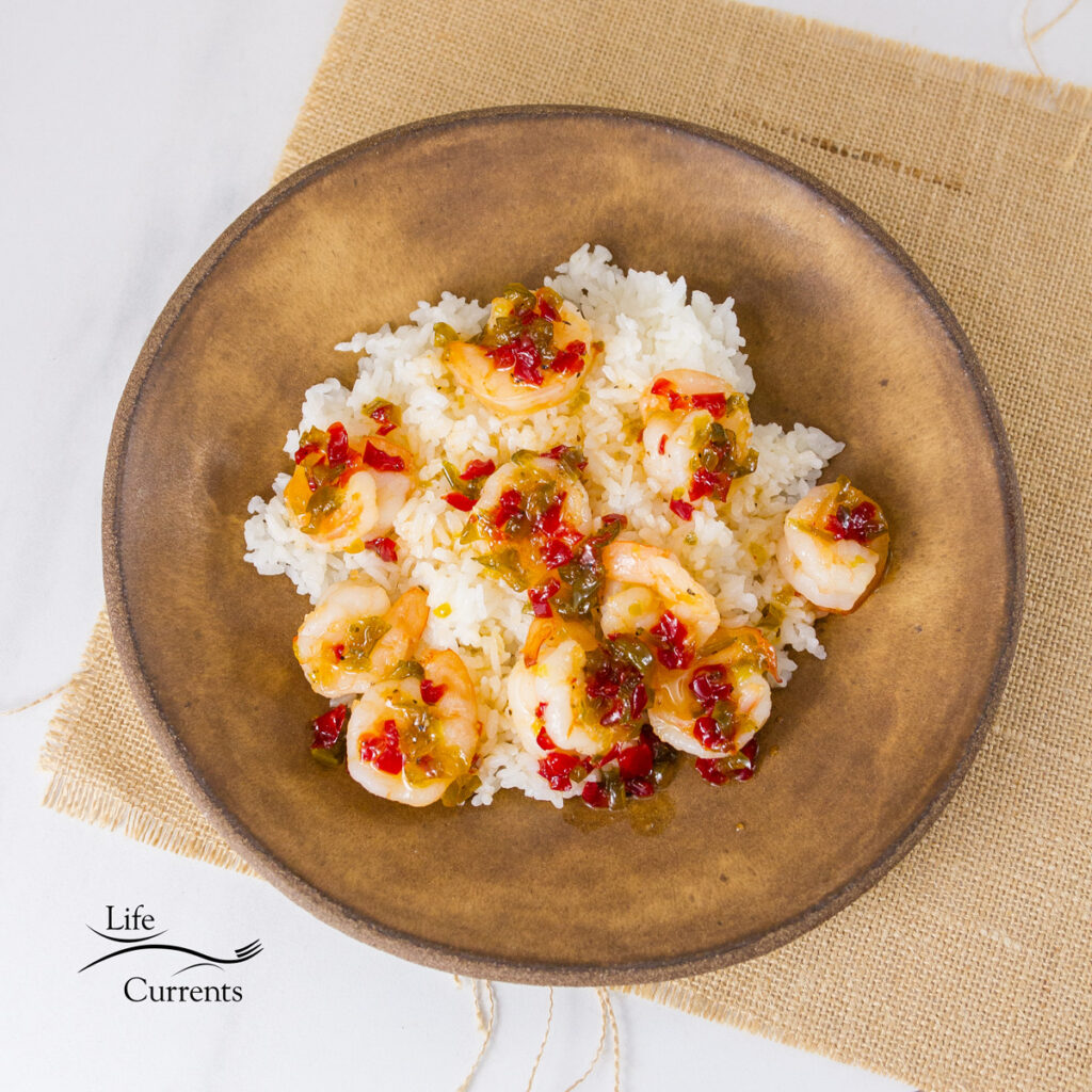 square crop of top down shrimp on rice with sauce in a brown bowl