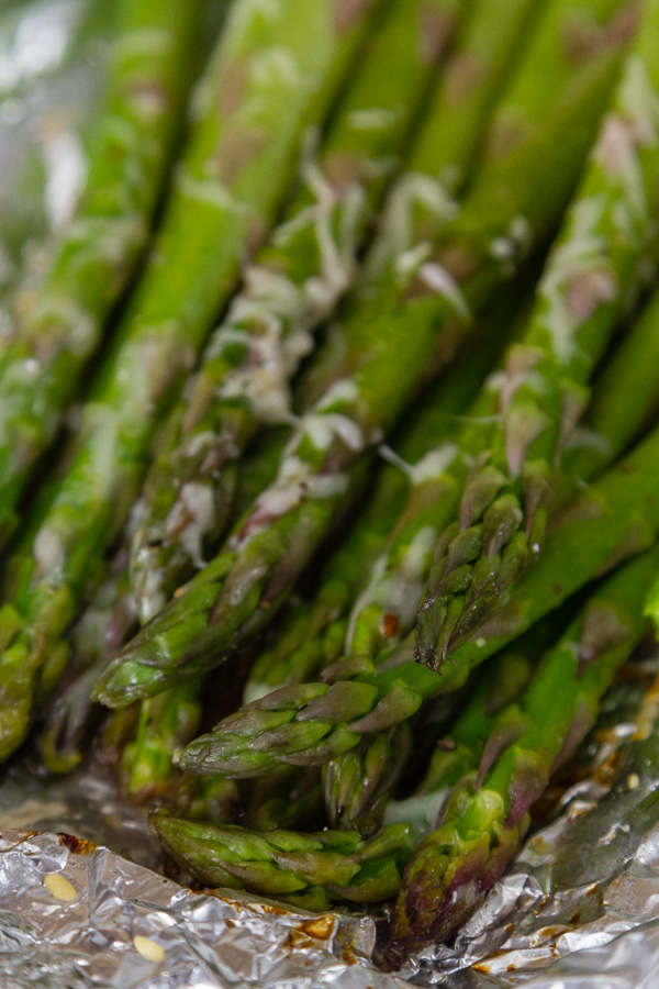 close up of cooked asparagus on foil with Parmesan cheese