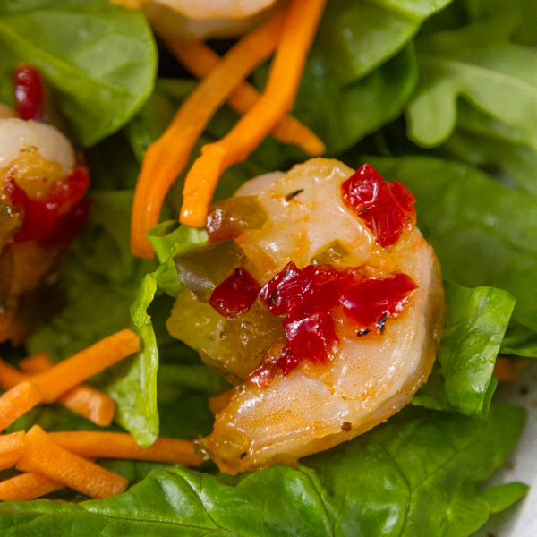 square crop of Pepper Jelly Shrimp on a bed of fresh spinach with shredded carrots 