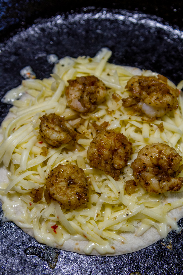 shrimp quesadillas cooking in a pan with lots of pepperjack cheese