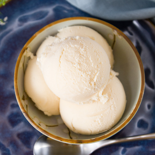 top down looking into a bowl of peach ice cream on a dark blue plate