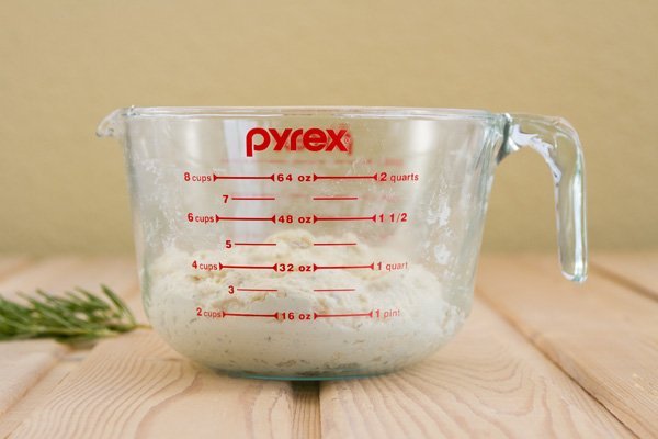 a 2-quart glass measuring cup with bread dough in it on a wood board