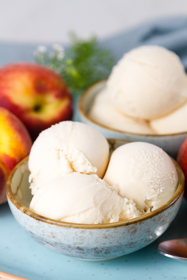 two bowls of ice cream with peaches and flowers around them