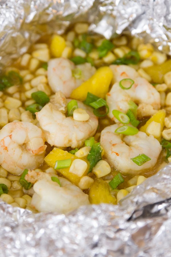 close up on an open Foil Packet of Caribbean Shrimp with shrimp, corn, pineapple, and green onions