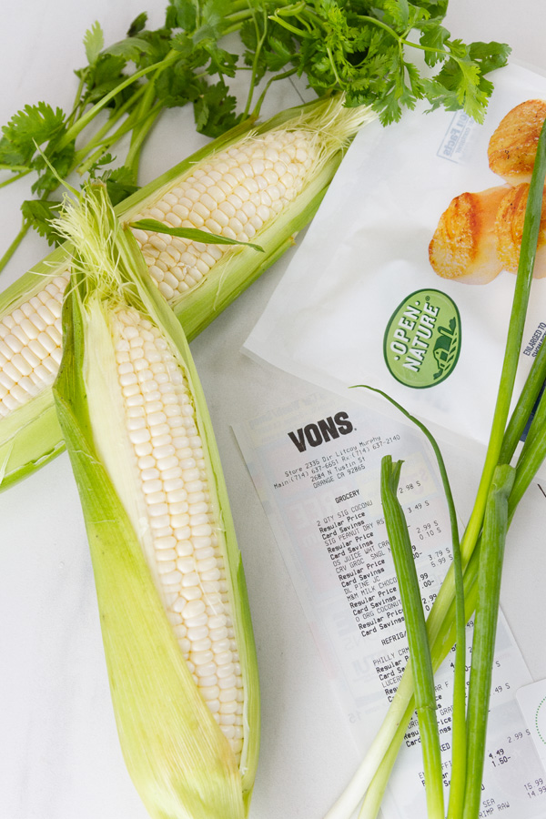 fresh ears of corn, a Vons reciept, a bag of Open Nature Seafood, and some green onions