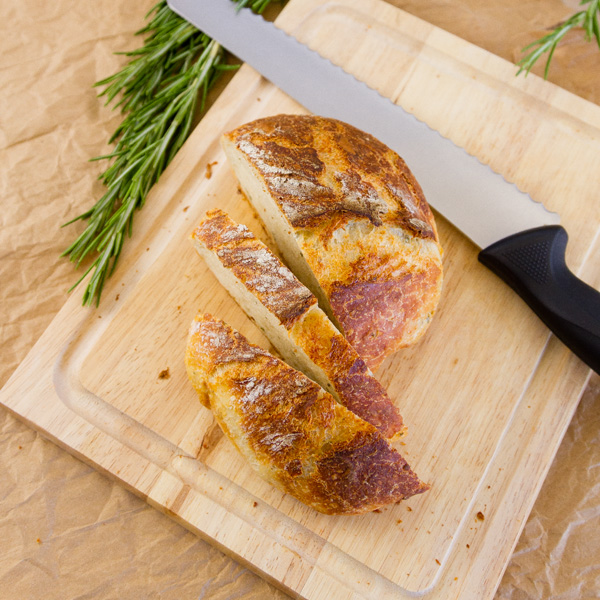 square crop, top down view, No-Knead Parmesan Rosemary Bread with a bread knife on a cutting board