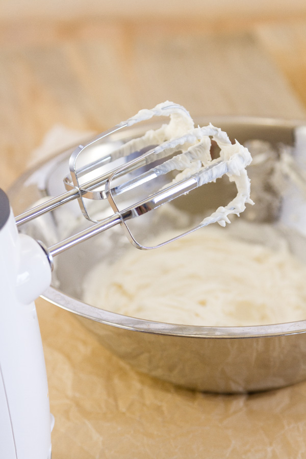 creme filling in a bowl with the hand beaters in the front. The beaters still have icing on them