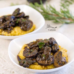 square crop of Mushroom Ragout Over Creamy Polenta in two bowls with fresh rosemary in the background