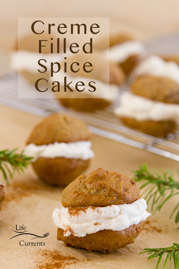 Creme Filled Spice Cakes on parchment paper and some on a cooling rack with evergreen boughs next to them. Title on image