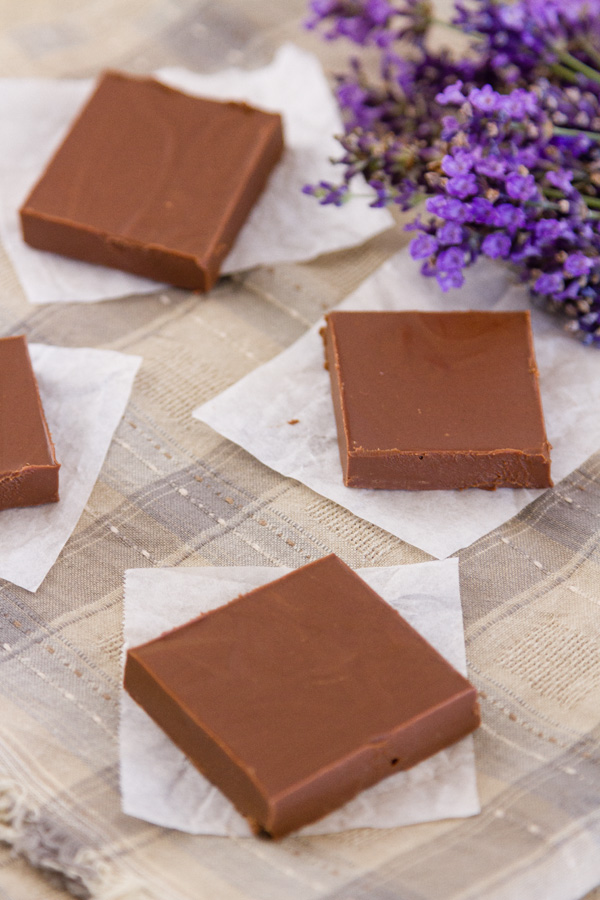 4 pieces of fudge on parchment paper on a cloth with lavender in the background