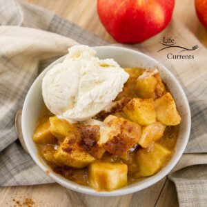 square crop of Peanut Butter Caramel Apples in a bowl with ice cream on a napkin and apples in the background