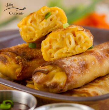 square crop of Mac and Cheese Egg Rolls on a serving plate garnished with green onions
