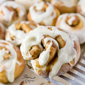 a cinnamon roll being lifted from the pan