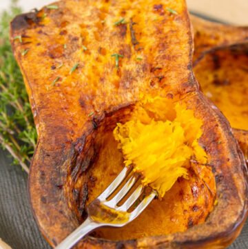 a fork full of roasted butternut squash taken out of the whole cooked squash