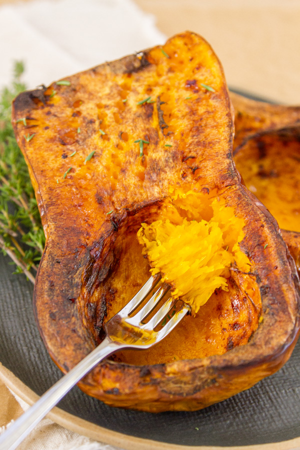 a fork full of roasted butternut squash taken out of the whole cooked squash.