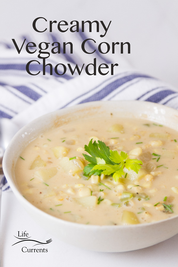 bowl of corn chowder on a blue striped towel with title, Creamy Vegan Corn Chowder, and logo