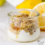 yougurt topped with wheat germ and honey with lemons and flowers in the background