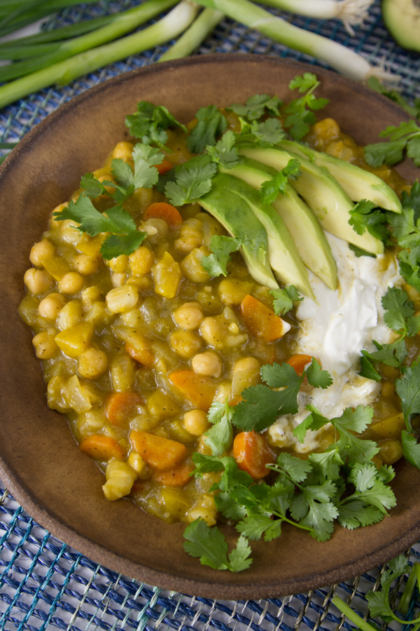 stew in a brown bowl garnished with avocado, cilantro, and sour cream