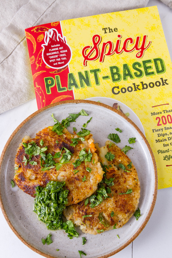 new cookbook, The Spicy Plant-Based Cookbook with potato fritters on a plate on top of the cookbook