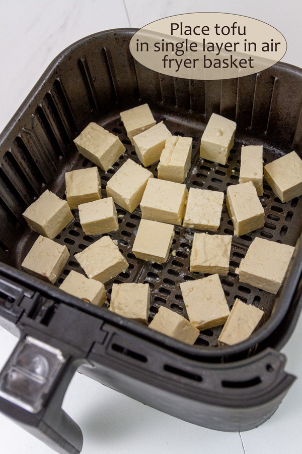 cubed tofu in an air fryer basket.