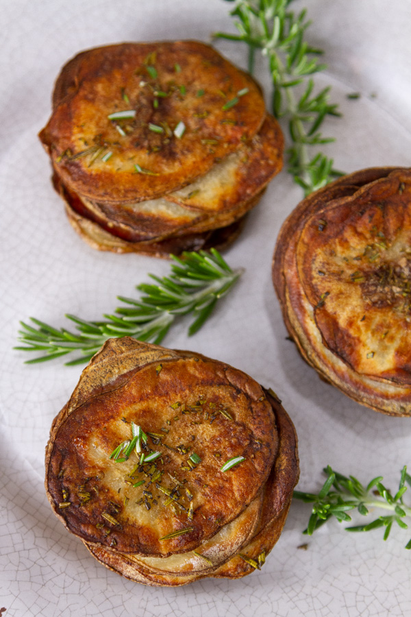 Three stacked cooked potatoes with rresh rosemary.