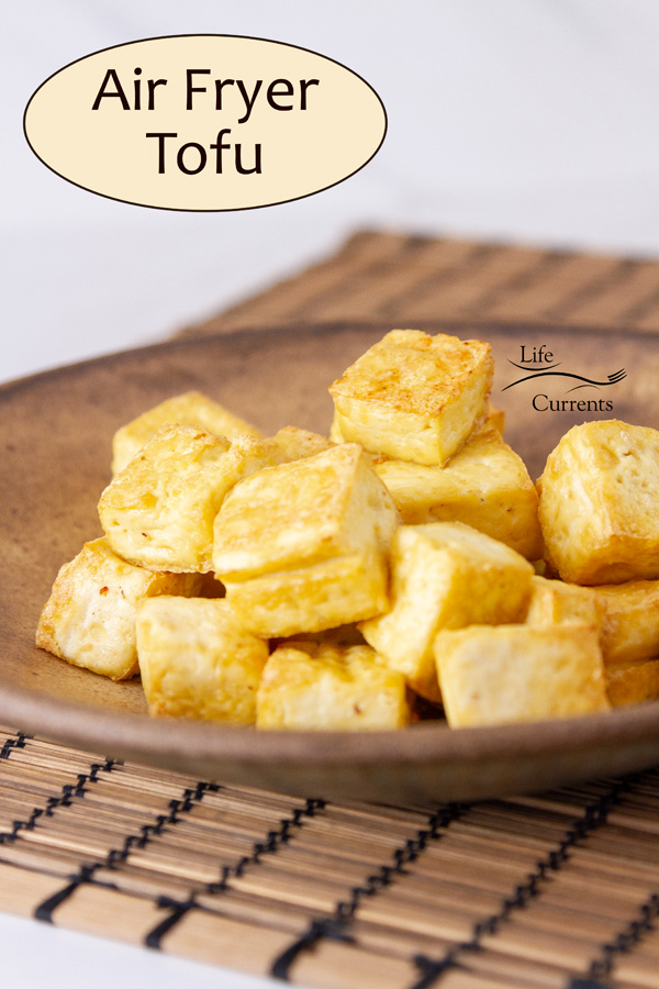 cooked browned tofu on a brown bowl on a mat with title on image: Air Fryer Tofu.