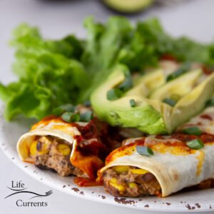 square crop of enchiladas on a plate with avocado slices and a salad