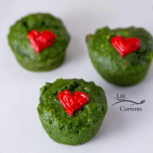 three green muffins with red icing hearts, square crop.