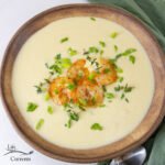 square crop of leek soup in a bowl with shrimp and herbs