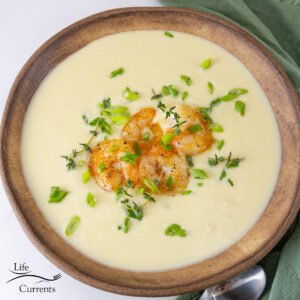 square crop of leek soup in a bowl with shrimp and herbs